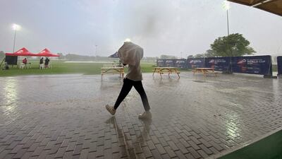 A person takes cover from heavy rain at the Sevens Stadium in Dubai on Monday. Photo: Antonie Robertson / The National