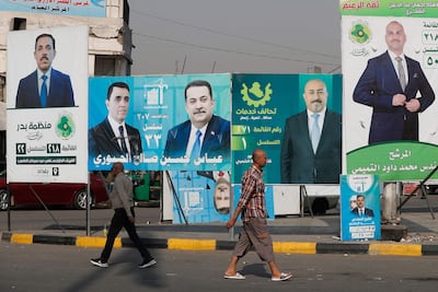 People walk past campaign posters in Baghdad ahead of Iraq's parliamentary elections. AFP