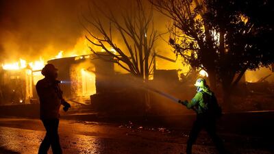 Firefighters hose down flames as a home burns in in Los Angeles as more wild fires struck California this week. The state's biggest power firm filed for bankruptcy earlier this year and has said it could take a decade to repair local grids. AP Photo.