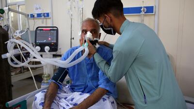 Mohammad Amin is helped by his son in the ICU ward for COVID-19 patients at the Afghan-Japan Communicable Disease Hospital.
