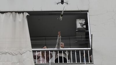 A woman on her balcony reaches out to catch a rose delivered to her via a drone on Mother's day, in the Lebanese coastal city of Jounieh, north of the capital Beirut as people remain indoors in an effort to limit the spread of the novel coronavirus. Three young Lebanese came up with the idea of delivering roses attached to drones, offered to mothers by their children as a surprise gift. The funds collected from this initiative will be donated to the Lebanese Red Cross to help fight against the CIVID-19 pandemic. AFP