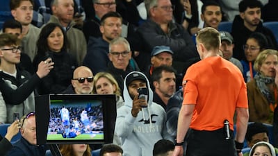 Referee Michael Salisbury watches the VAR screen prior to giving a red card to Chelsea defender Reece James. AFP