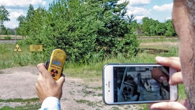 A tourist photographs the radiation reading on his dosimeter near a field with a high radiation level near Pripyat. Bloomberg