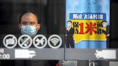 A security guard stands at the entrance of a shopping mall near a sign reminding people to keep at least one meter distance from each other in Beijing. AP