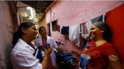 Usha Devi, right, who was suffering from cervical cancer, talks with health workers from Tata Memorial Hospital in a slum in Mumbai. Rafiq Maqbool / AP Photo