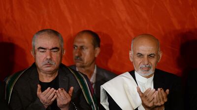 Abdul Rashid Dostum and Afghan President Ashraf Ghani pray during a press conference in Kabul in 2014. AFP
