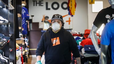 A worker wears protective equipment after assisting a customer select her purchases from curb-side at The Loop fashion and shoe store as businesses slowly begin to reopen in Yonkers city, New York. AP