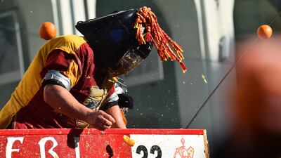 A participant wearing a helmet is hit with oranges. Reuters