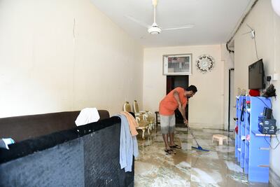 Tahidul Islam, from Bangladesh, clears up, after the damage caused by the floods in Kalba, Sharjah. Khushnum Bhandari / The National