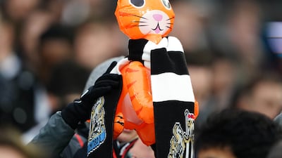 A Newcastle United fan in the crowd holds up an inflatable cat. PA