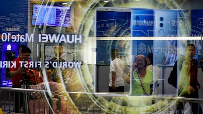 An elderly Filipinoholds a mobile phone next to a Huawei billboard reflected on a glass panel in Manila, Philippines. Francis R Malasig / EPA