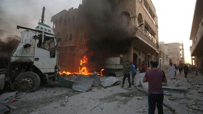 People walk amidst rubble as part of a building burns following a reported airstrike by Syrian regime forces in Maaret Al Numan, Idlib. AFP