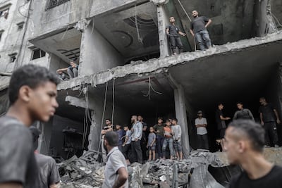 Palestinians in the remains of a destroyed building following an Israeli air strike at the Al Shati refugee camp in Gaza city. Bloomberg