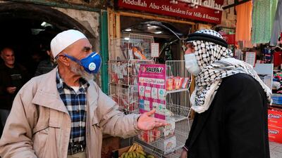 Palestinian men talk in the centre of the occupied West Bank town of Hebron during the coronavirus pandemic. AFP