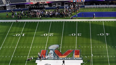 Workers paint a logo on the field at SoFi Stadium as members of the media watch days before Super Bowl LVI. AP