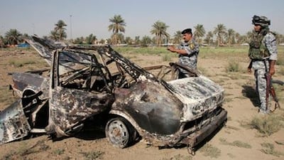 Iraqi policemen examine a car that was used in an attack at an Iraqi checkpoint. Some stolen cars are being used as car bombs.