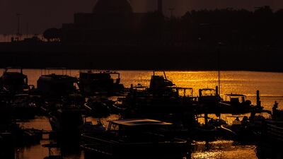 The sun rises behind the skyscrapers along the Corniche in Abu Dhabi.
