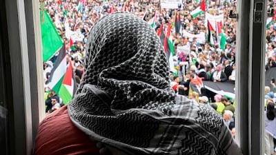 A man wearing a keffiyeh looks out at protesters. AFP
