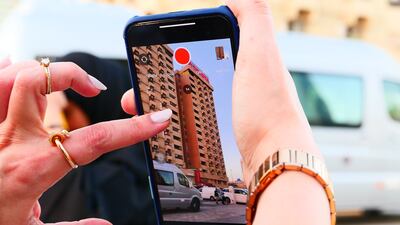 A woman takes a photo of the building.