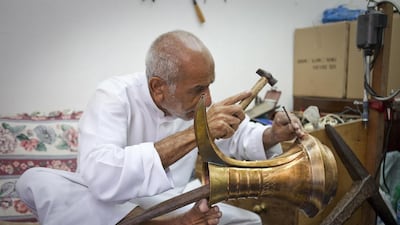 Ismail Ali Al Hassan, 74, delicately hammers patterns on one of his dallahs. The third-generation dallah craftsman is the last man in the UAE to make the traditional coffee pots by hand. Razan Alzayani / The National
