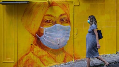 A pregnant woman wearing a face mask as a precautionary measure walks past a street mural in Hong Kong. AFP