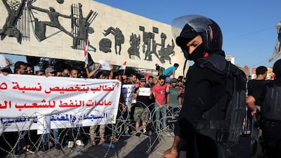 Iraqi riot police stand guard in front of Iraqi protesters during a demonstration at Tahrir square, central Baghdad. EPA