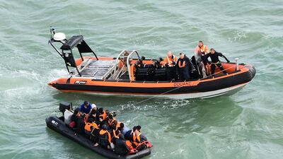 Migrants sitting in an inflatable dinghy are rescued by French coast guards while trying to cross the Channel to Britain in August. AFP
