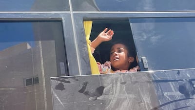 A Sudanese girl with British citizenship waves goodbye to loved ones from a bus before being processed for evacuation. Reuters