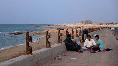 Men sit on the sidewalk of a beach in Sirte, Libya. Reuters