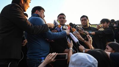 Police Lieutenant Kiatisuk "Zico" Senamuang, centre, a Thai football manager speaks to journalists outside the temple. AFP