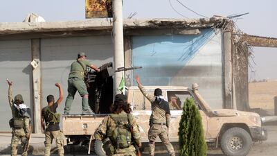 Turkey-backed Syrian fighters gesture as their comrade fires a weapon mounted on a truck in the town of Tal Abyad, Syria. Reuters