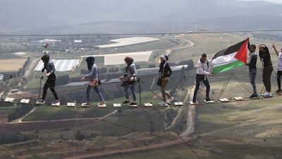 Palestinians walk on a suspension bridge, overlooking Israeli settlements during a protest marking the 67th anniversary of Nakba at Iran park in the southern Lebanese-Israeli border village of Maroun el-Rass, Lebanon. Mohammed Zaatari / AP Photo