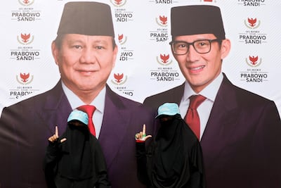 Women gesture next to a banner of presidential candidate Prabowo Subianto, and his running mate Sandiaga Uno, as they attend a campaign rally in Bandung. Reuters