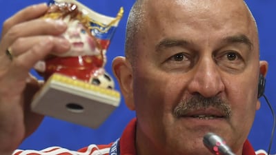Russia manager Stanislav Cherchesov holds up a small figurine dressed in Russia red and replete with flag and football, dubbed “Success”, a dainty ornament sculpted by an artist working at a Moscow university, which was presented to him by a member of the media. Francisco Leong / AFP