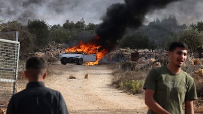Palestinians stand near a burning car reportedly set alight by Israeli settlers trying to disrupt the olive harvest in Turmus Ayya. AFP
