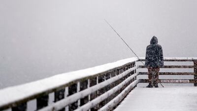 Hershel Odle looks out toward the cityscape lost in a whiteout as he fishes from a pier during a snowstorm in Seattle. AP