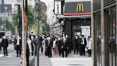 Pedestrians wearing protective masks wait to cross a road in Shinbashi in Tokyo, Japan. Bloomberg