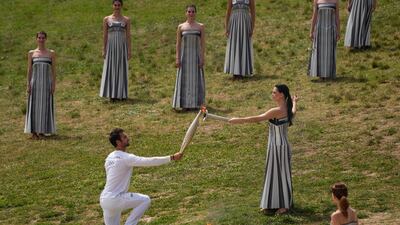 Mina gives the flame to the first torch bearer, Greek olympic gold medalist Stefanos Ntouskos. AP