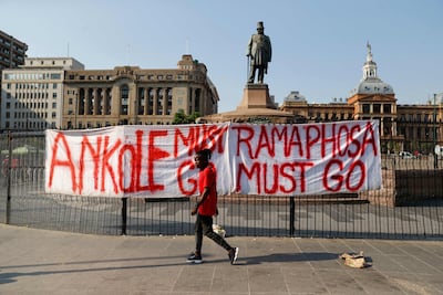 A member of the the Economic Freedom Fighters (EFF) walks past a banner that reads "Ramaphosa must go" at Church Square in Pretoria on March 20, 2023 during a "national shut-down" called by their party. (Photo by PHILL MAGAKOE / AFP)