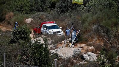 UN peacekeepers stand next to a Hezbollah flag raised on the Lebanese side of the border with Israel, near the northern Israeli settlement of Shtula, on Tuesday. AFP