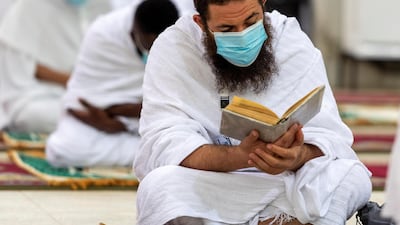 A Muslim pilgrim wearing a protective mask, reads the Quran. REUTERS