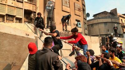 Anti-government protesters try to pull down concrete walls during clashes with security forces in Baghdad. AP Photo