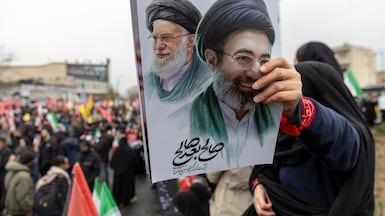 A woman holds a poster of assassinated supreme leader Ali Khamenei and his successor, Mojtaba Khamenei, during pro-regime rallies in Tehran. Getty Images
