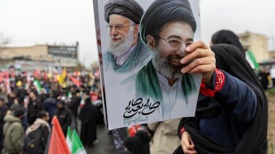 A woman holds a poster of assassinated supreme leader Ali Khamenei and his successor, Mojtaba Khamenei, during pro-regime rallies in Tehran. Getty Images