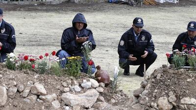 Policemen pray next to graves of the miners. Tolga Bozoglu / EPA / May 17, 2014