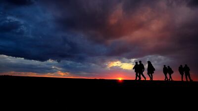 People walk by the sea during the sunset in southeast resort of Ayia Napa in the eastern Mediterranean island of Cyprus. AP