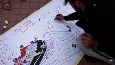 A migrant writes on a banner in tribute to migrants who died crossing the channel, in Calais, northern France, on August 13. AFP