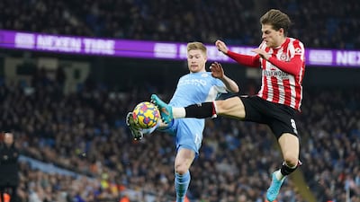 De Bruyne is tackled by Brentford's Jensen. AP