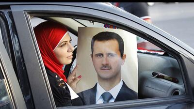 A Syrian woman holds a portrait of Syria's President Bashar al-Assad as pro-regime supporters parade their cars in Damascus to celebrate Assad's 48th birthday. Anwar Amro / AFP