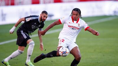 Jules Kounde of Sevilla FC takes a shot under pressure from Karim Benzema. Getty